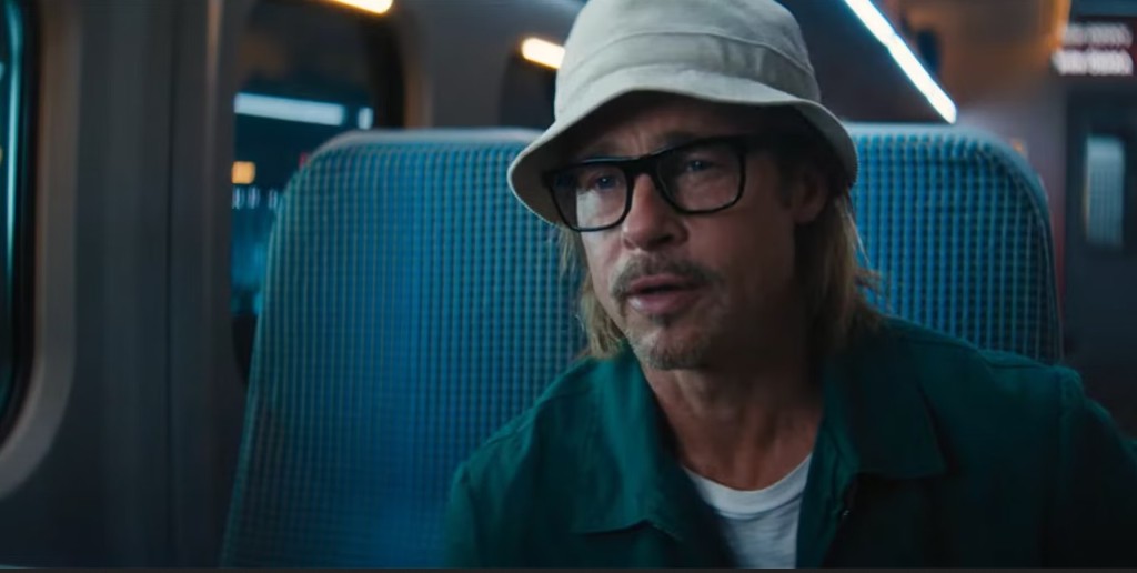 Brad Pitt with long hair wearing a bucket hat and the douchiest glasses ever on a train